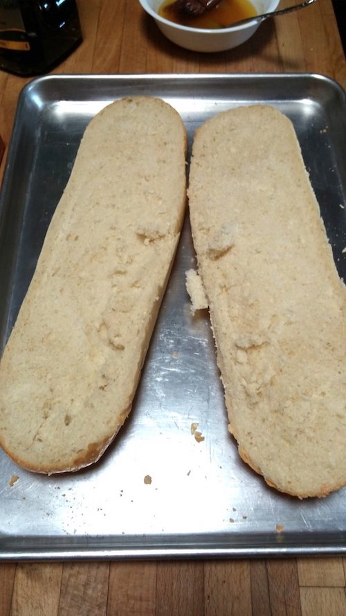 1 loaf of french bread cut in half length-wise to be made into garlic bread. Sitting on an aluminum cookie sheet.