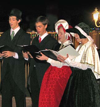 Four Christmas carolers (2 guys and 2 girls) singing at a local resort.