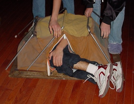 A memorable Christmas Present. Teen age boy curled up inside of a small sample camping tent.