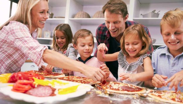 Around the dinner table: Making Eating Together Fun. A family making pizzas for dinner together.