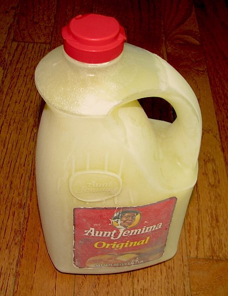 A half gallon of frozen milk in an Aunt Jemima syrup container