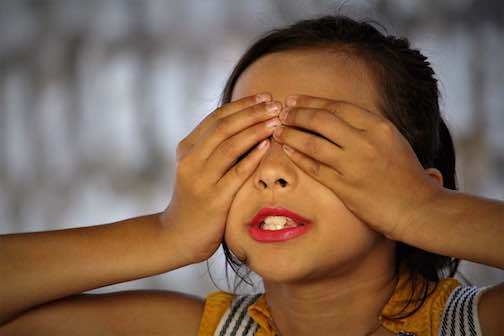 A girl covering her eyes guessing while playing a game on family game night.