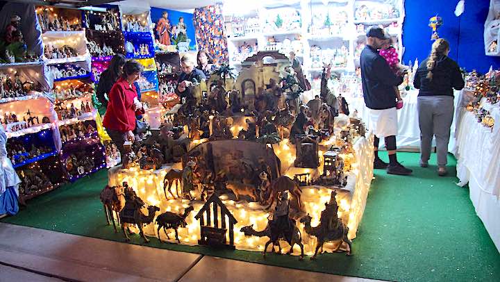 Many nativity scenes on display in a garage.