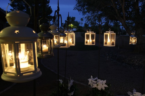 Eight white lanterns hanging on shepherds crooks with lit candles inside.
