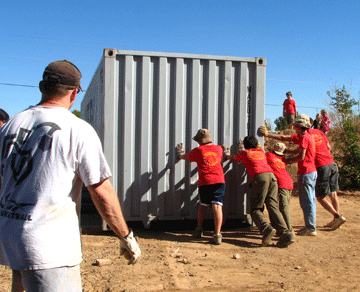 A team of kids moving a second storage container.
