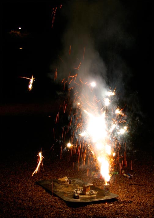Ground fireworks shooting white sparks into the air.