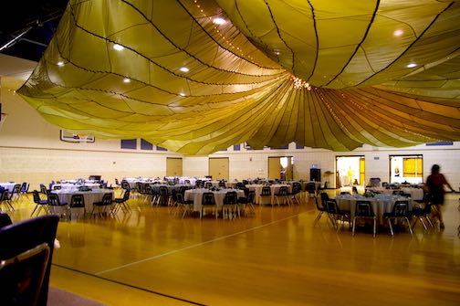 A large cargo parachute hung over a banquet hall for a wedding reception