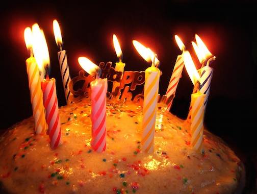 A birthday cake with 10 lit candles on it.