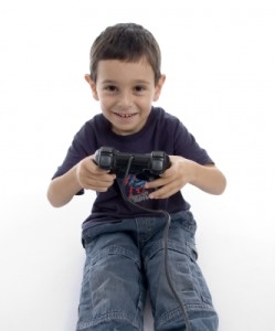 Toddler boy with a video controller in his hands, smiling.