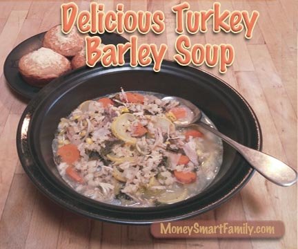 A black bowl filled with turkey barley soup and 3 cornbread muffins on another dish.