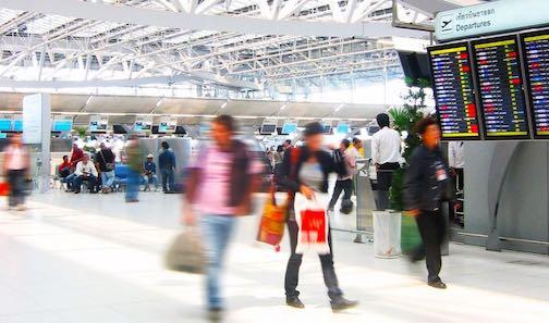 Travelers pulling luggage through an airport terminal.